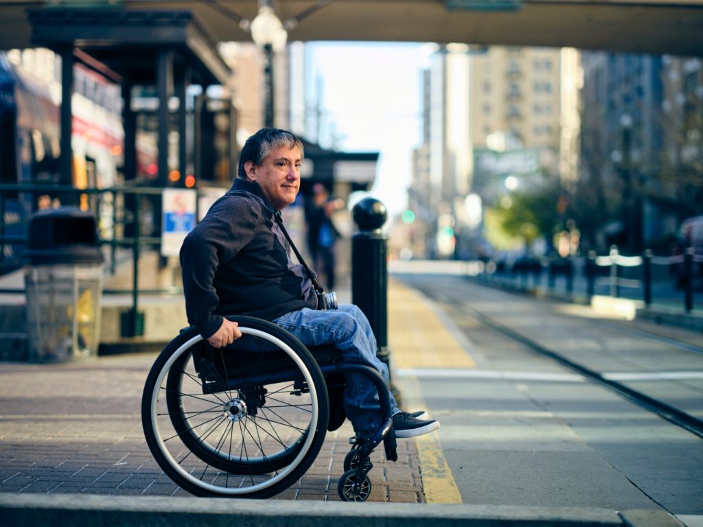 A wheelchair user in a town waiting to cross the road